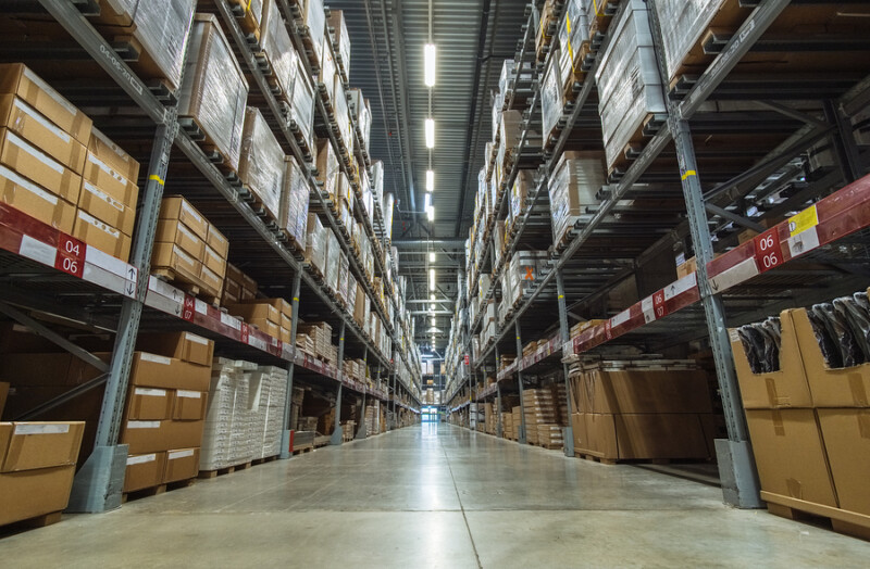Large warehouse logistic or distribution center. Interior of warehouse with rows of shelves with big boxes.