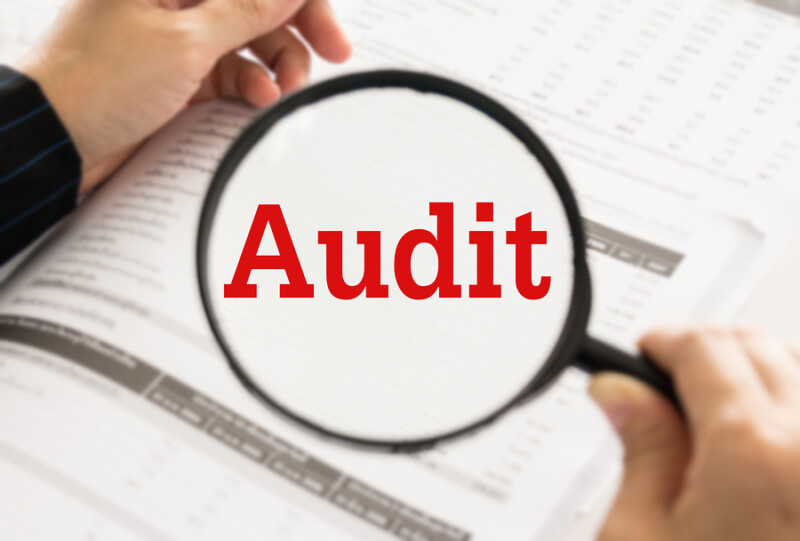 Audit concept. Auditor or IRS using magnifier auditing revenue in financial statement auditing tax process.